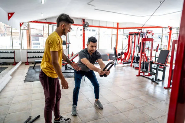 One-on-one fitness coach demonstrating proper form to a male trainee