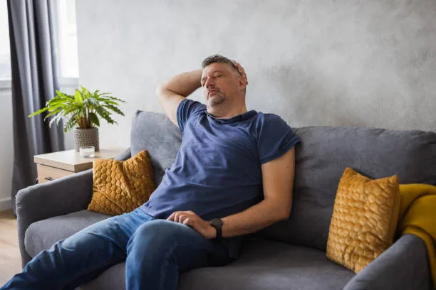 Man sitting on a couch looking exhausted