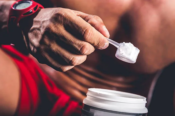 Person mixing creatine supplement into water before a workout
