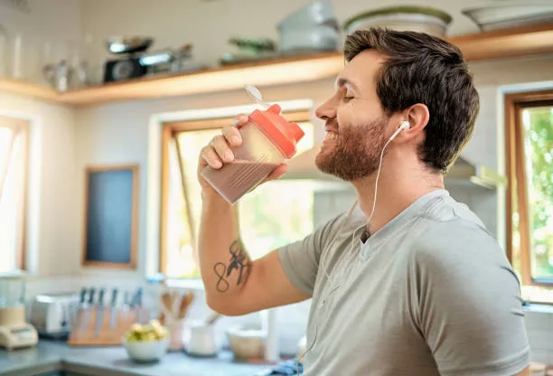 Man drinking a creatine shake post-fast in a bright kitchen